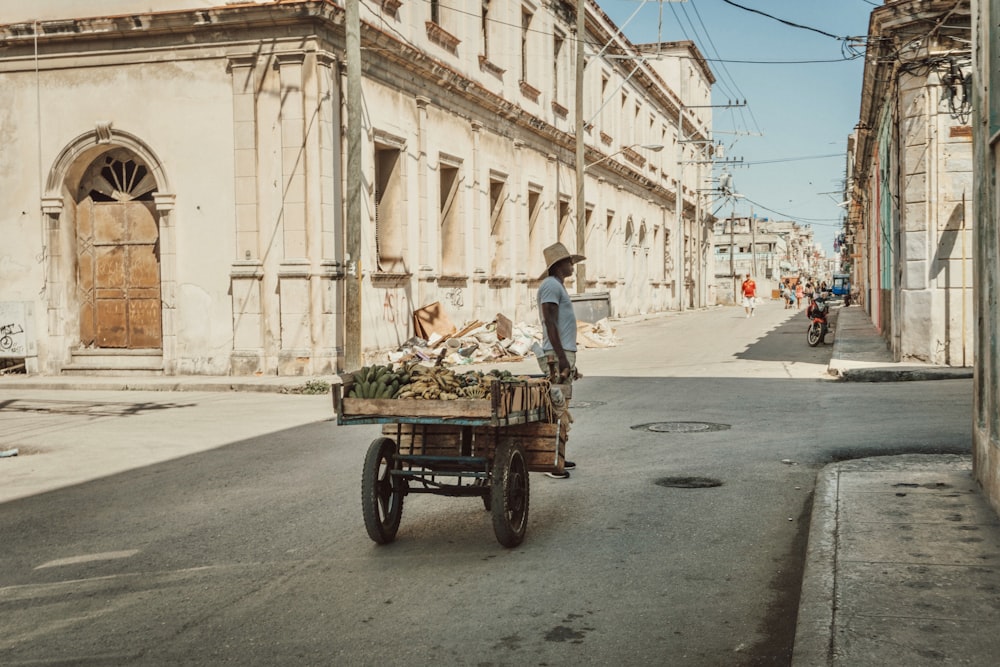 man in blue shirt and blue denim jeans riding on brown wooden cart in front of on with with with