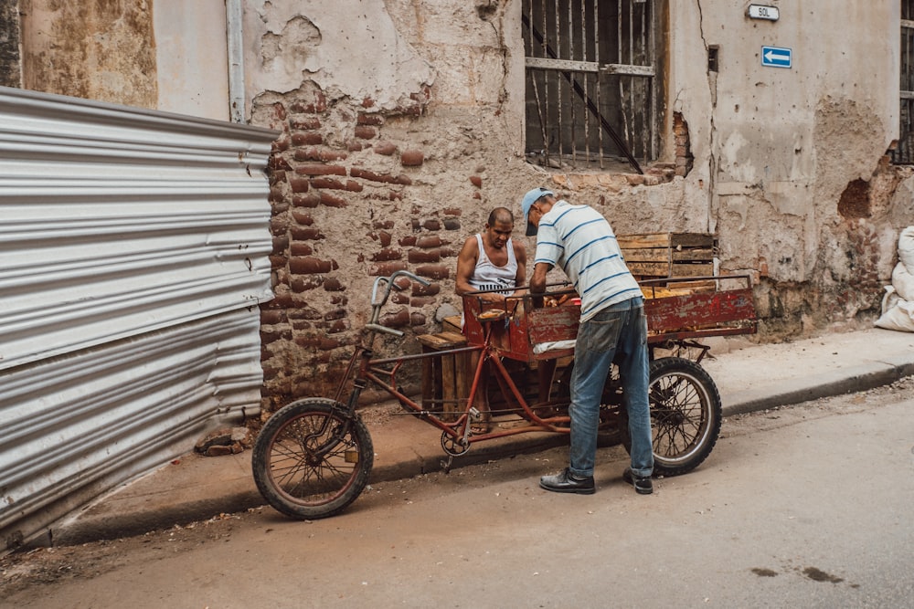 man in blue and white stripe shirt and blue denim jeans riding red and black bicycle