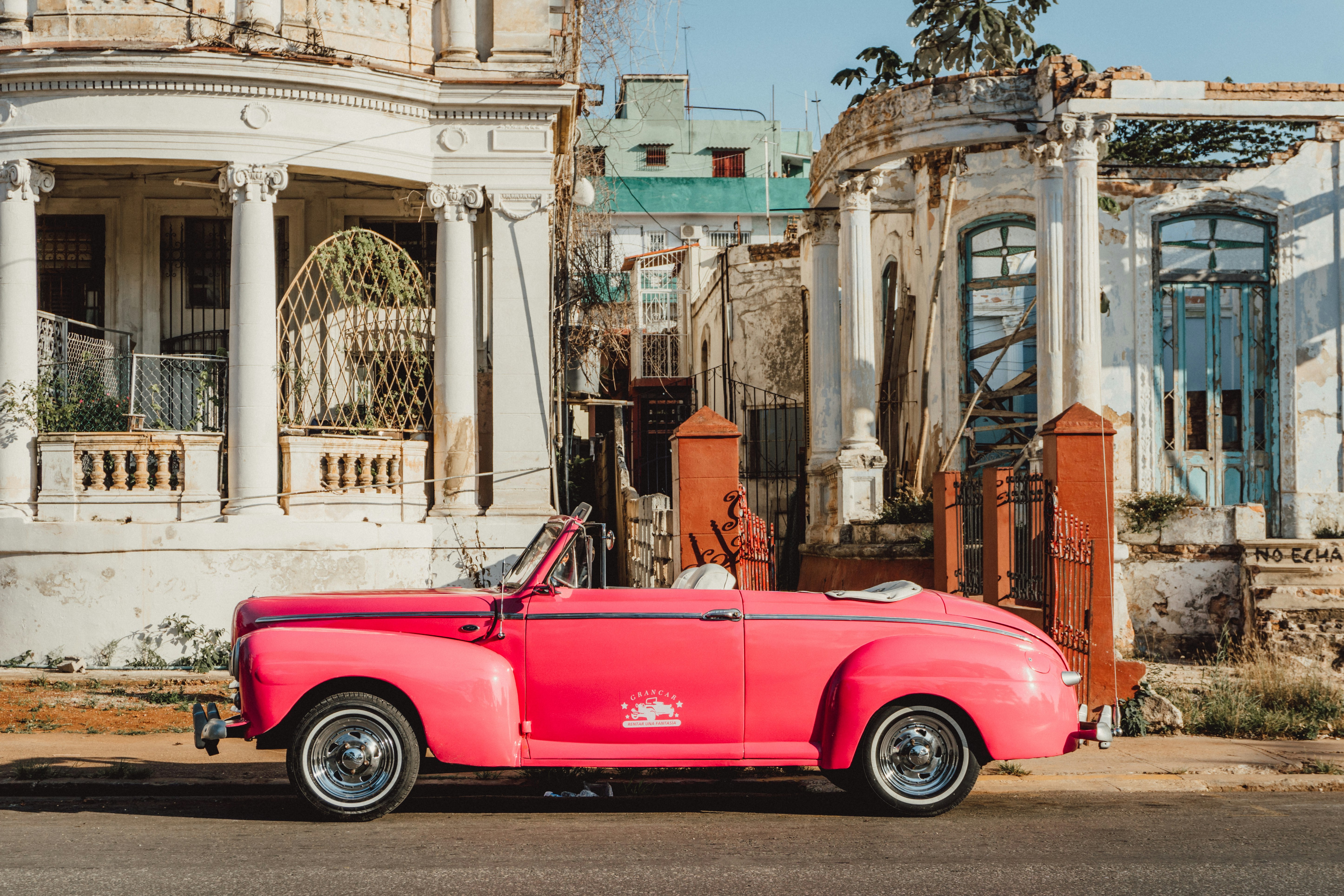 pink car parked in front of building during daytime