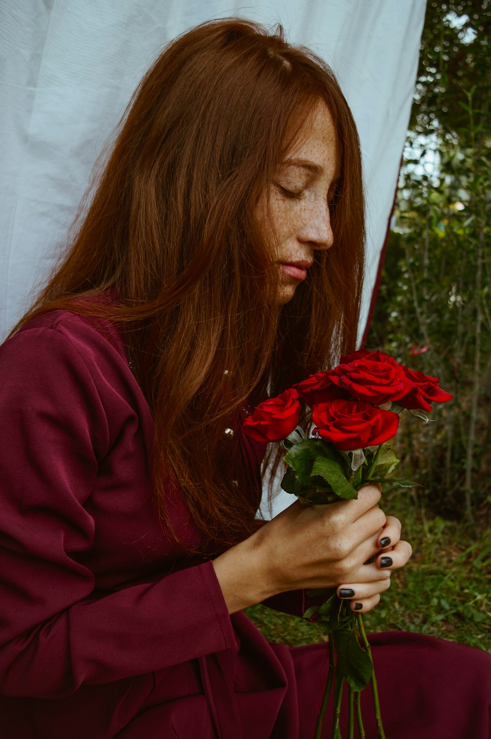woman in red long sleeve shirt holding red rose