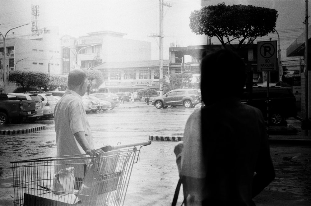 grayscale photo of man and woman walking on sidewalk