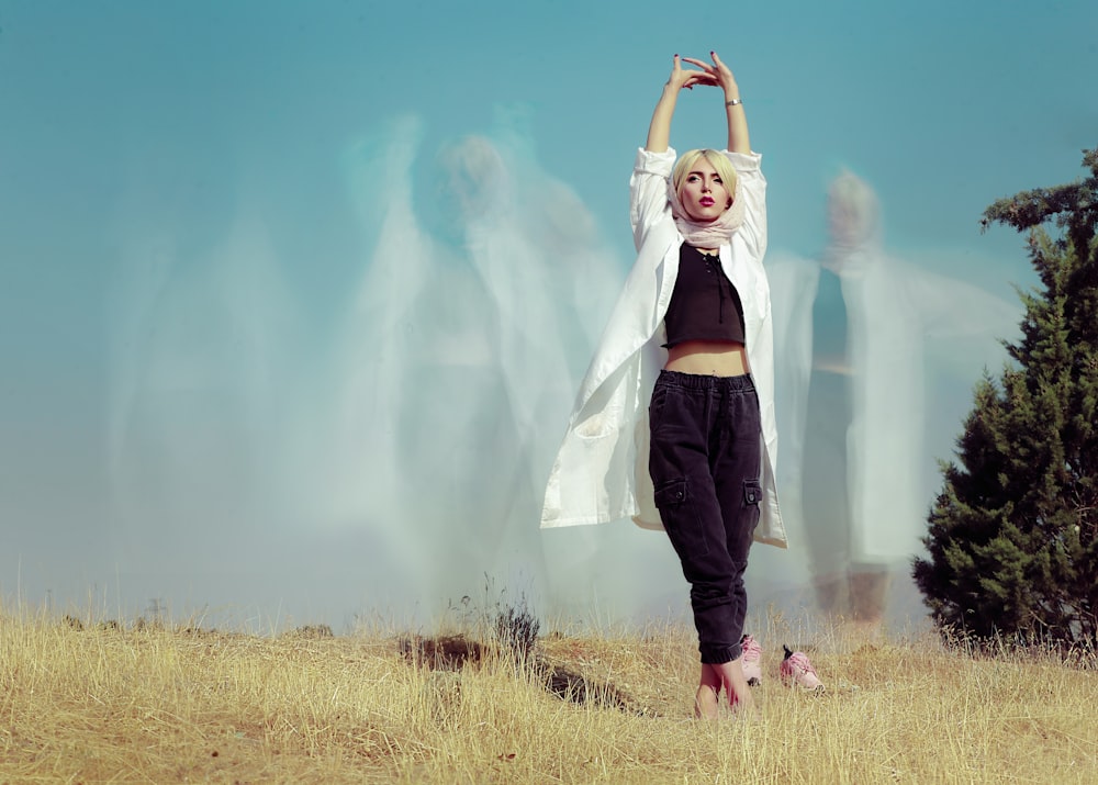 woman in white long sleeve shirt and black pants standing on green grass field during daytime