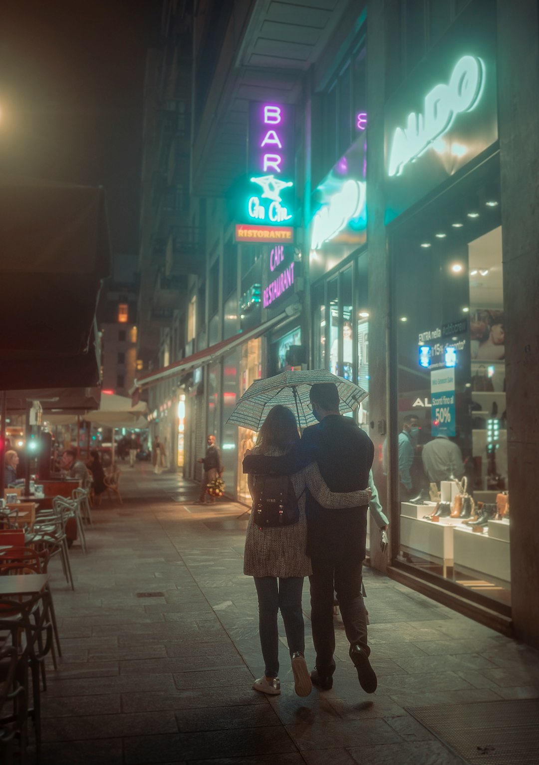 woman in black and white polka dot coat holding umbrella walking on sidewalk during night time