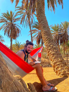 A traveler happily planning a trip on a laptop with tropical beach background.