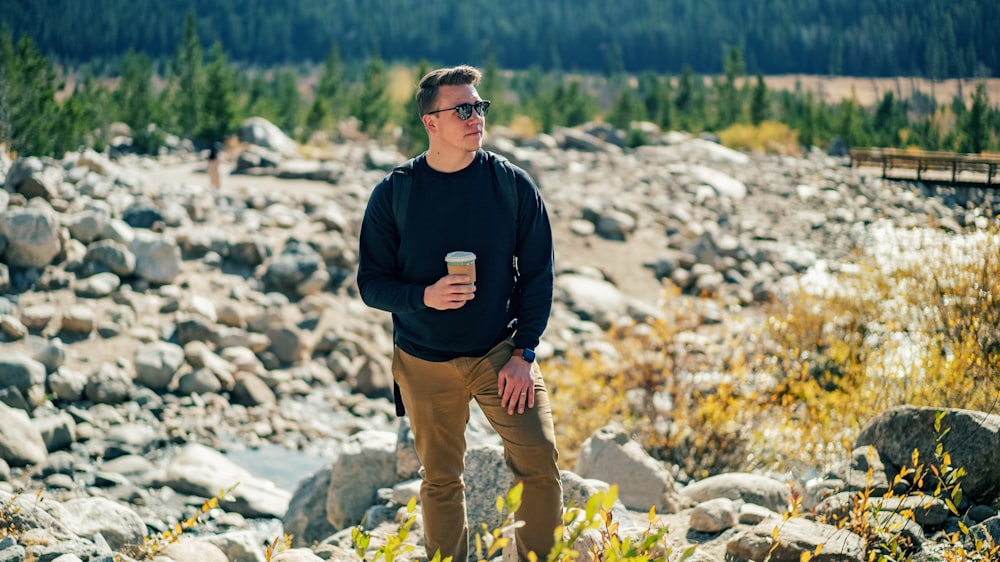 man in black jacket and brown pants standing on rocky ground during daytime