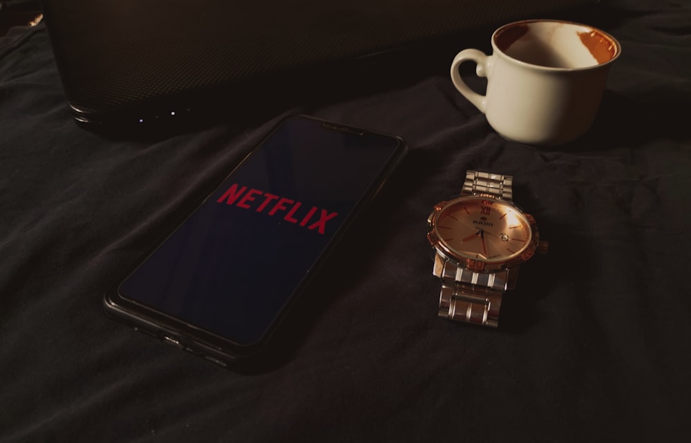 gold and silver round analog watch beside white ceramic mug