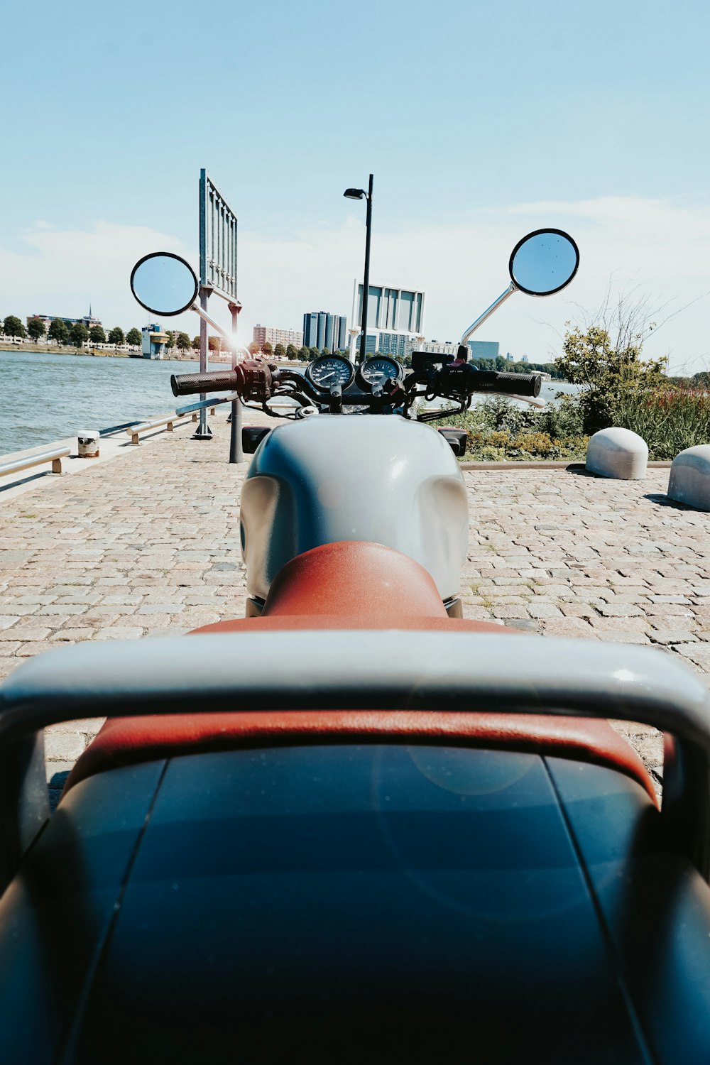 scooter bianco e rosso parcheggiato vicino a uno specchio d'acqua durante il giorno