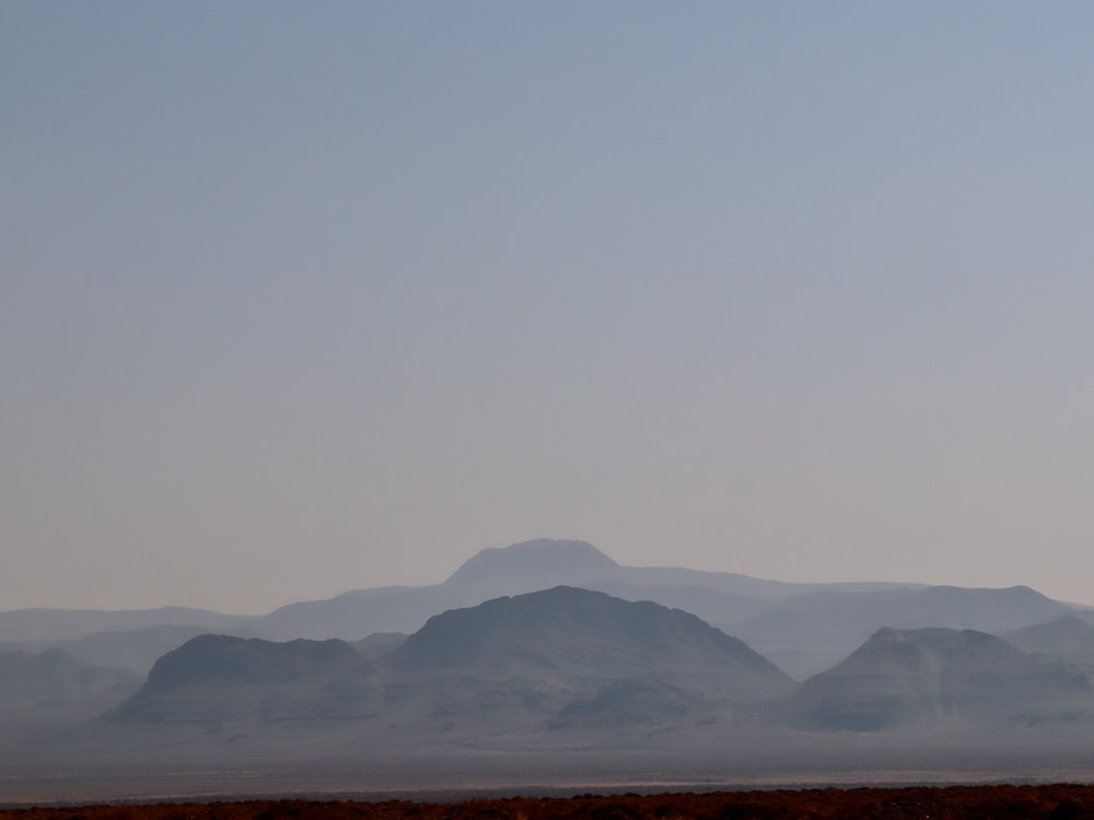 brown field near brown mountain under white sky during daytime