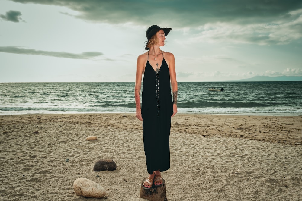 woman in black halter dress standing on beach during daytime