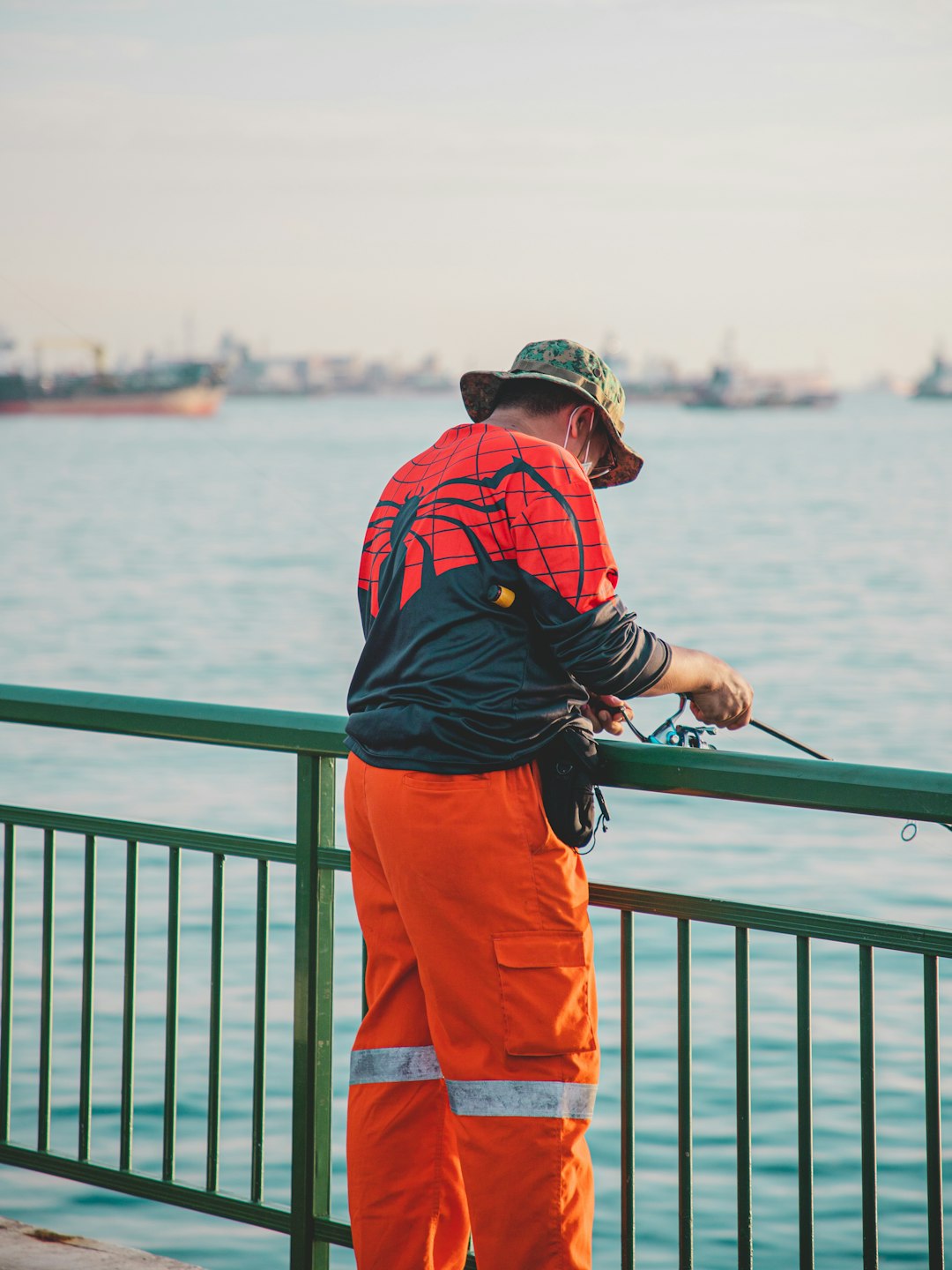 man in blue jacket and orange pants standing on boat during daytime