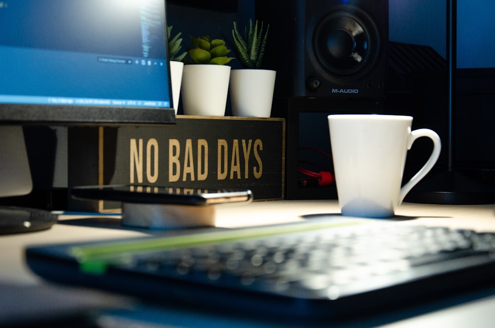 white ceramic mug beside black computer keyboard