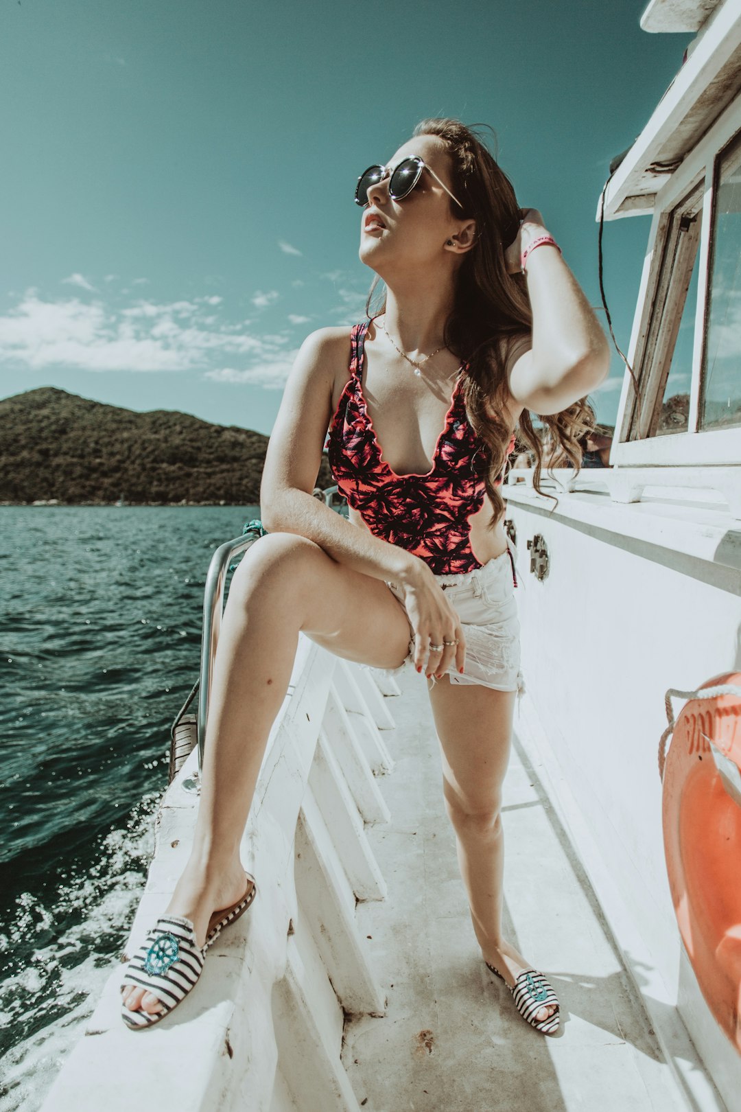 woman in red and white floral bikini sitting on white boat during daytime