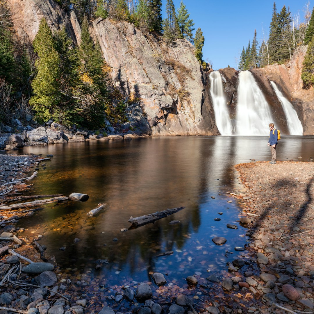 waterfalls near brown mountain under blue sky during daytime