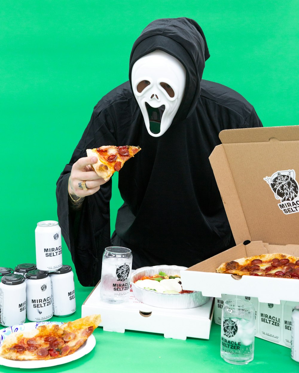 person in black and white mask holding brown carton box