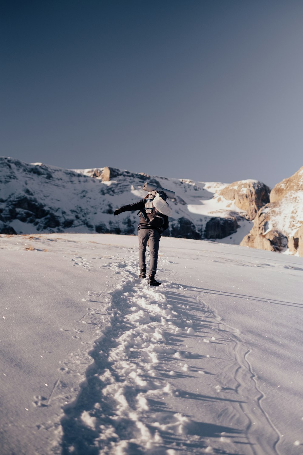 Persona in giacca nera e pantaloni neri in piedi su terreno coperto di neve durante il giorno