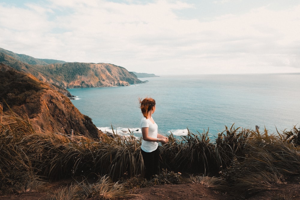 woman in white tank top sitting on brown rock