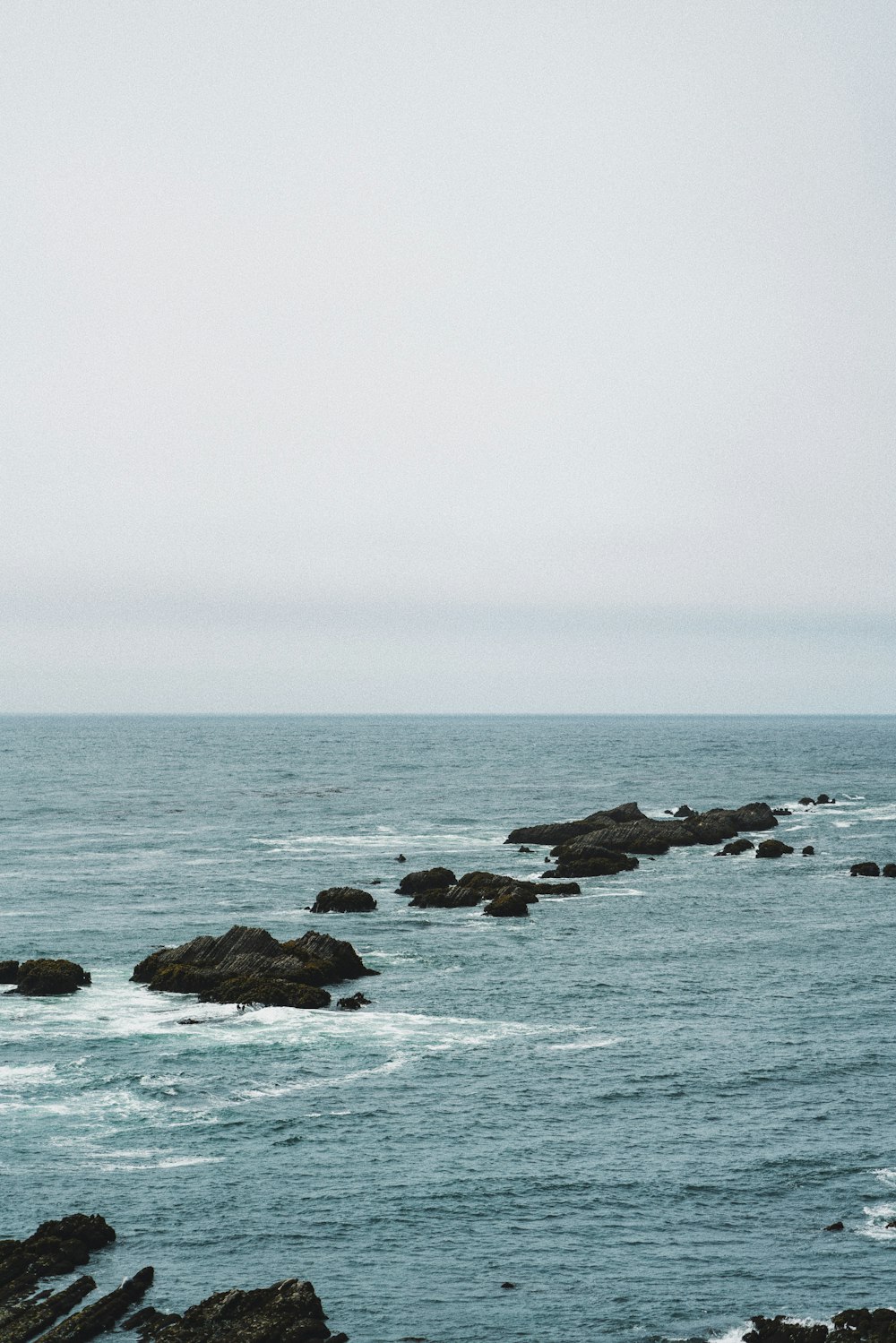 brown rock formation on sea under white sky during daytime