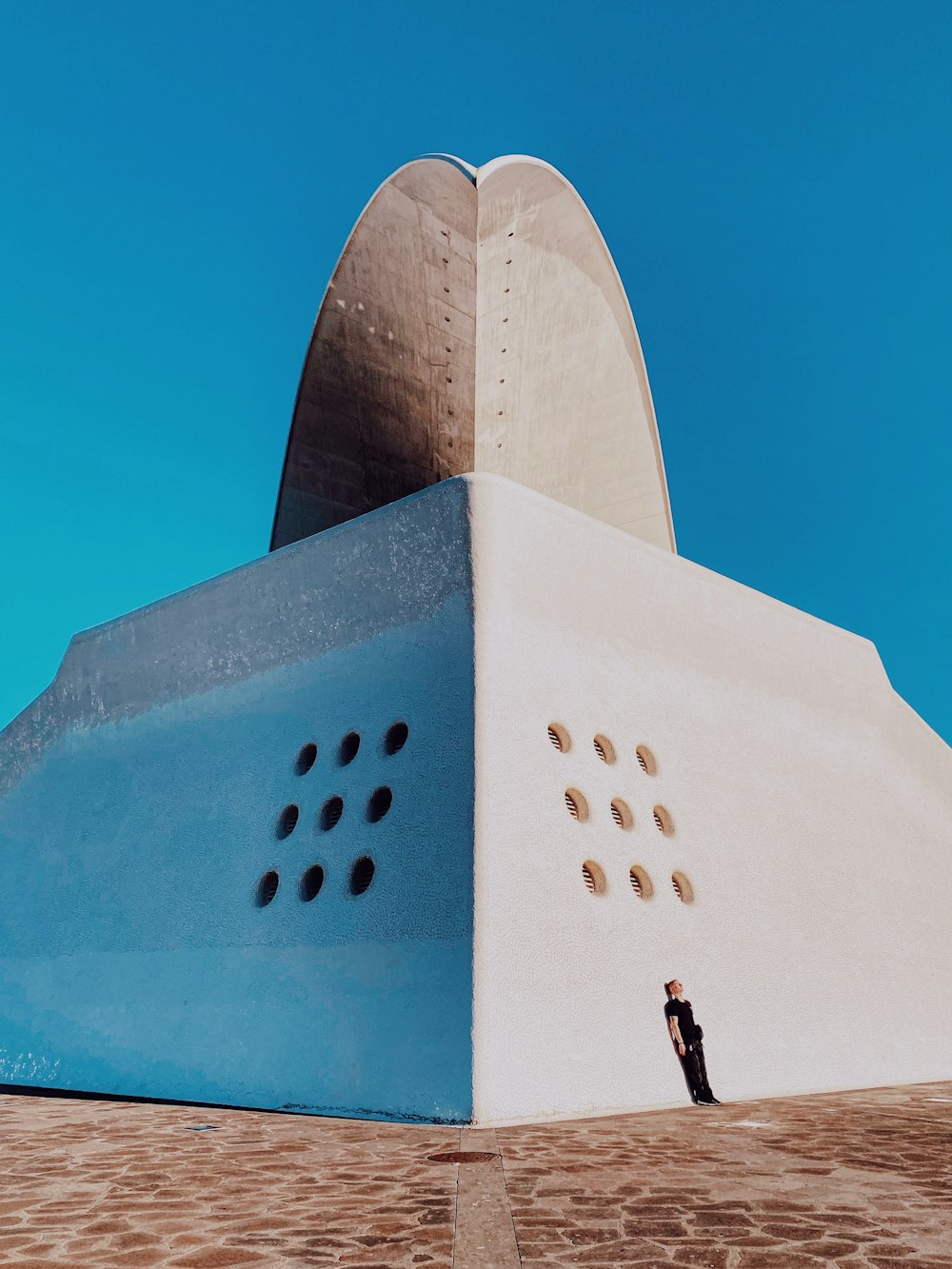 man standing on white concrete building under blue sky during daytime