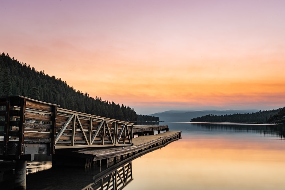 brown wooden dock on lake during sunset