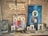 A wooden shelf displays religious icons and paintings, primarily depicting figures with halos, likely saints or religious figures. A string of rosary beads and various religious artifacts are arranged on the shelf alongside the images. Above, a wooden plaque with an inscription hangs on the wall.
