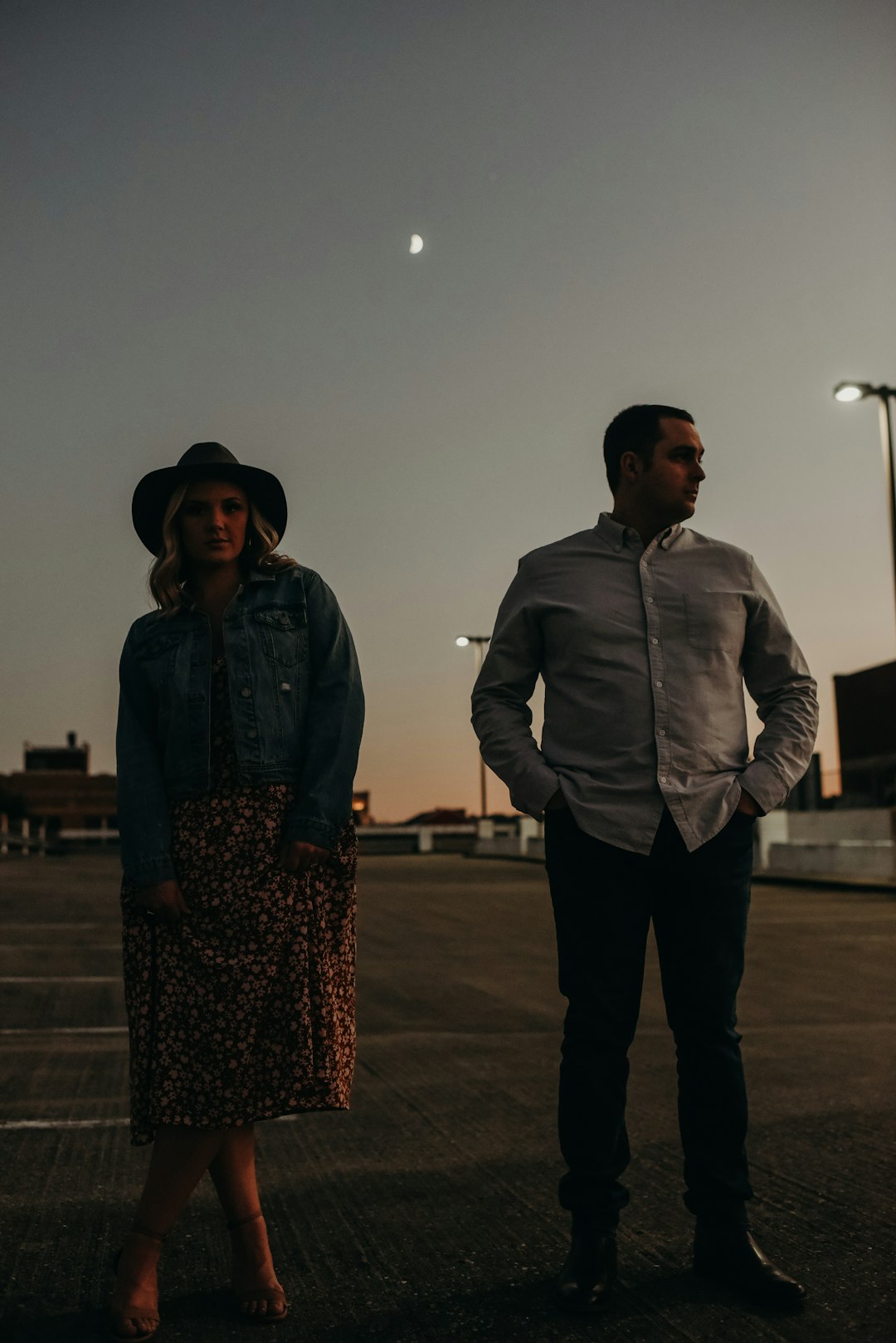 man in gray zip up jacket standing beside woman in black and white floral dress