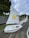A row of small white sailboats is lined up on a textured surface with green grass nearby. Each boat has a sail, with the nearest one featuring a cheerful yellow star carrying a basketball and branding for Southern Cross Travel Insurance. The sailboat is labeled 'ATLAS CONCRETE' in red letters on its side.