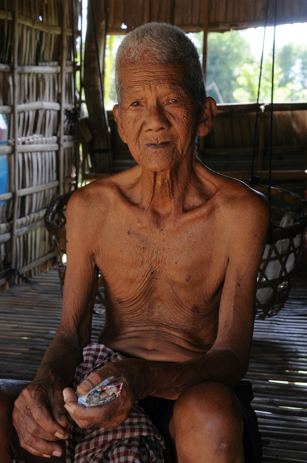 topless man sitting on brown wooden bench