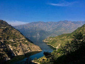 green mountains near lake under blue sky during daytime