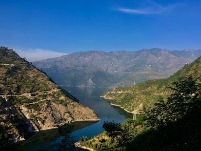 green mountains near lake under blue sky during daytime