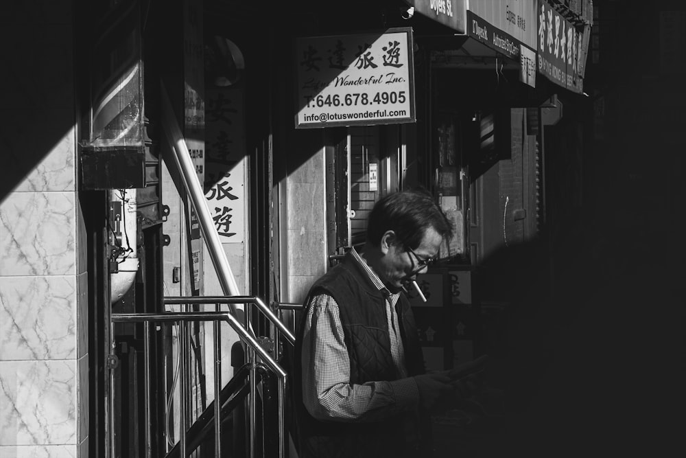 grayscale photo of woman in jacket standing near window