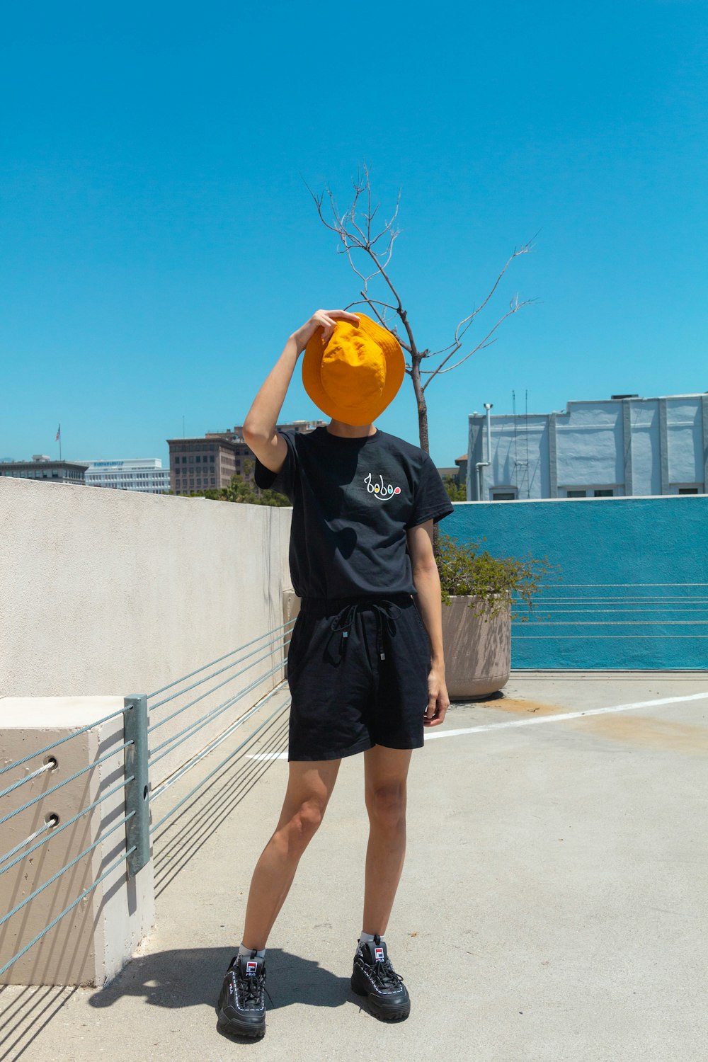 man in black t-shirt and black shorts holding yellow plastic bag