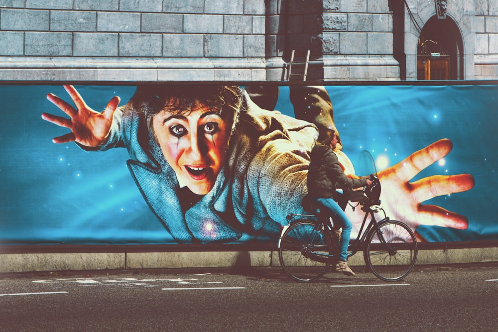 man riding bicycle with womans face graffiti