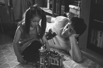 A playful scene of father and son building blocks together on the floor.