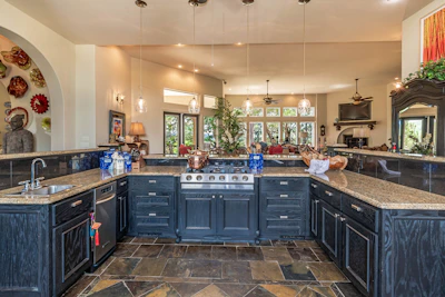 Interior shot of a spacious kitchen with navy blue cabinetry and gold fixtures.