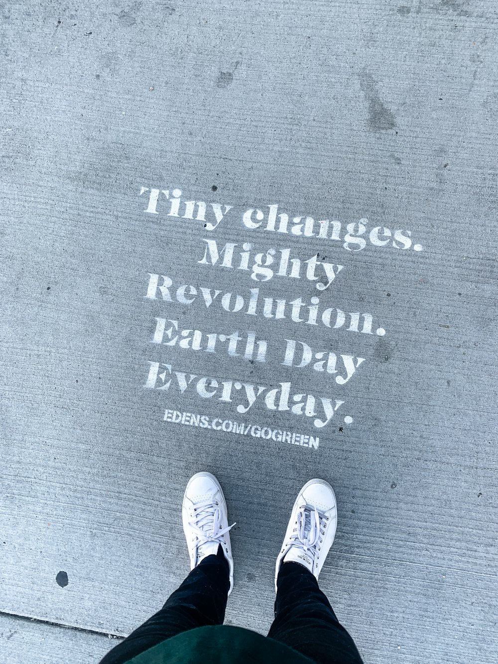 person wearing white and black sneakers standing on gray concrete floor