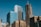 Tall modern skyscrapers with reflective glass facades against a clear blue sky, featuring multiple high-rise office buildings with visible logos such as OPTIV, POLSINELLI, and CHASE. The structures exhibit both vertical and horizontal architectural designs.