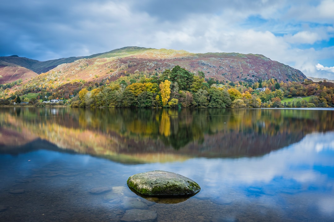 green and brown mountain beside body of water during daytime