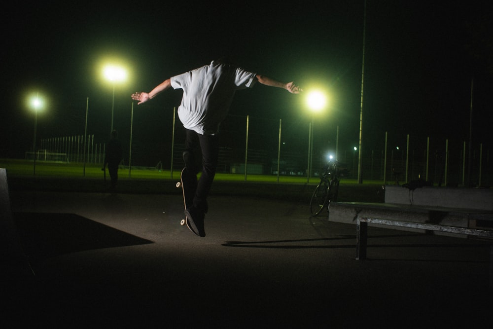 man in white long sleeve shirt and black pants playing basketball during night time