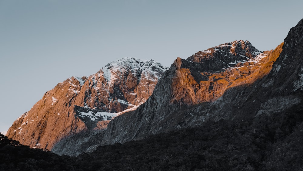 Montaña rocosa marrón y blanca bajo cielo gris