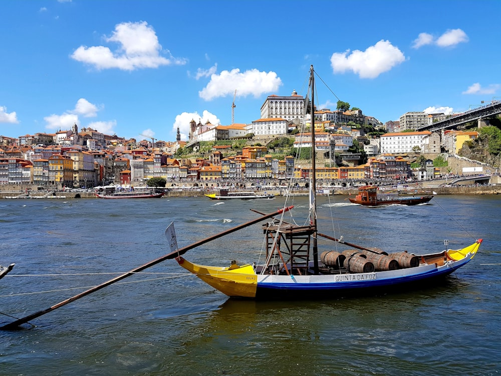 blue and yellow boat on water near city buildings during daytime