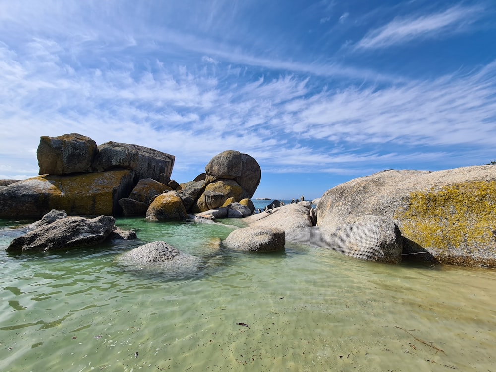 brown rocks on body of water under blue sky during daytime