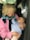 An elderly person is holding a baby in their arms inside a car. Both appear to be engaged in a gentle interaction, with the baby looking up at the elder.