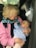 An elderly person is holding a baby in their arms inside a car. Both appear to be engaged in a gentle interaction, with the baby looking up at the elder.