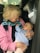 An elderly person is holding a baby in their arms inside a car. Both appear to be engaged in a gentle interaction, with the baby looking up at the elder.