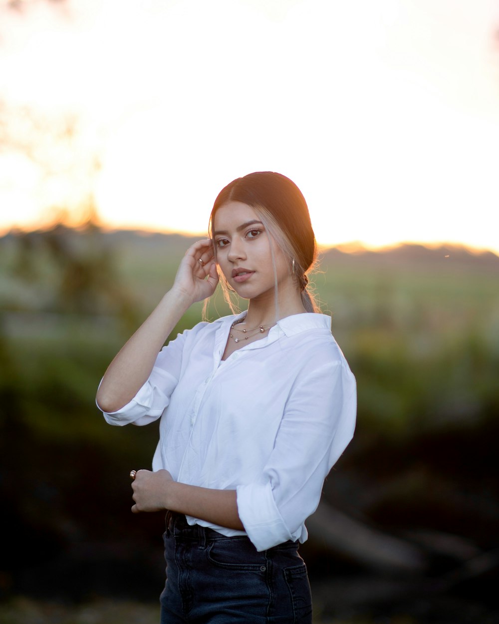 woman in white dress shirt and orange knit cap standing near body of water during daytime