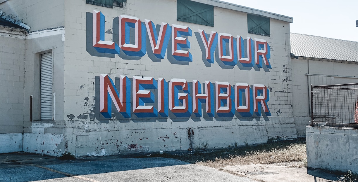 a large sign on the side of a building that says love your neighbor