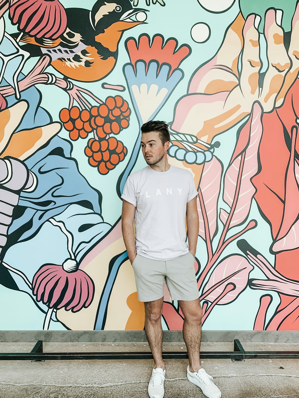man in white crew neck t-shirt standing beside wall with graffiti