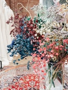 A vibrant arrangement of dried flowers in a decorative vase on a soft beige background.