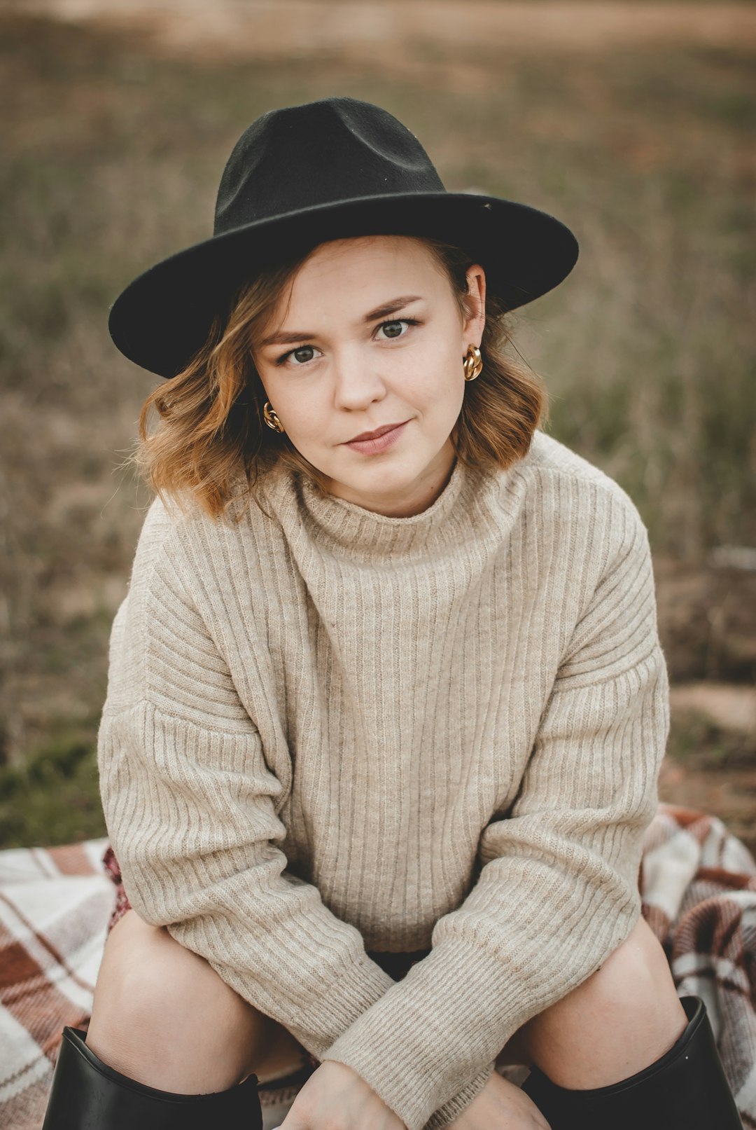 woman in beige sweater and black fedora hat