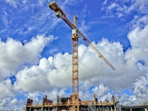 yellow crane under blue sky and white clouds during daytime